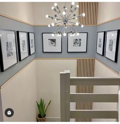 a staircase with pictures on the wall and a chandelier