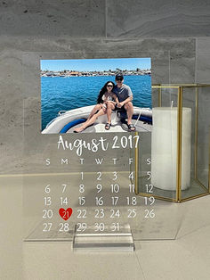 a couple sitting on a boat in the water next to a calendar and candle holder