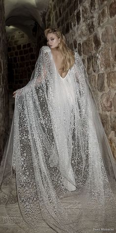 a woman in a white dress with a long veil on her head and hands behind her back