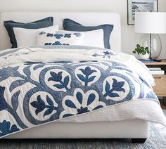 a bed with blue and white quilts on it