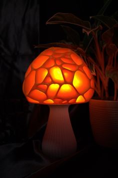 a mushroom shaped lamp sitting next to a potted plant on a table in the dark