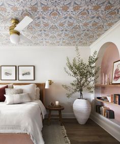 a bed room with a neatly made bed and a potted plant