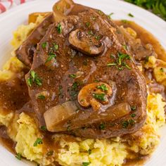 a white plate topped with mashed potatoes covered in gravy and mushroom toppings