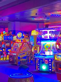 several brightly lit games are on display in an indoor area with neon lights and blue carpet