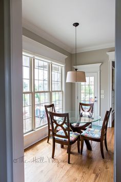 a dining room table with four chairs and a lamp hanging from the ceiling above it