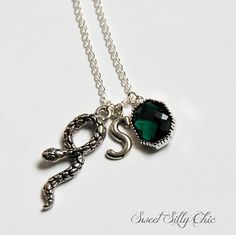 a necklace with an initial charm and a green stone