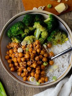 a bowl filled with broccoli, chickpeas and white rice on top of a wooden table