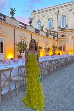 a woman in a yellow dress standing next to tables