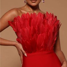 a woman in a red dress with feathers on it