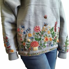 the back of a woman's hoodie with flowers and bugs on it,