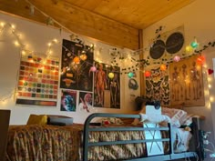 a bedroom with lights strung from the ceiling and pictures on the wall above it,