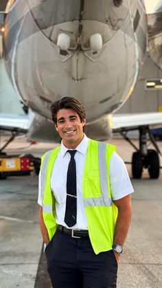 a man wearing a safety vest standing in front of an airplane on the tarmac