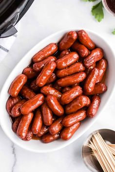 a white bowl filled with hot dogs next to some chopsticks and an air fryer