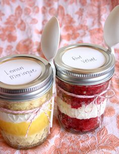 two mason jars with spoons and labels on them sitting on a tablecloth covered surface