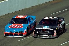 two racing cars driving on a track next to each other with numbers painted on them