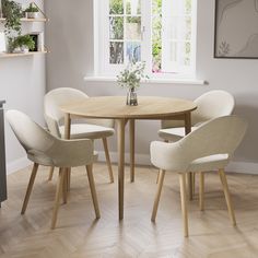 a table with four chairs around it in front of a window and potted plant