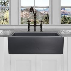 a kitchen sink with two faucets in front of the window and mountain view