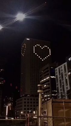 the city skyline is lit up at night with bright lights and buildings in the background