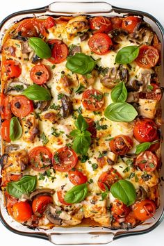 a casserole dish with tomatoes, mushrooms, and basil leaves on the top