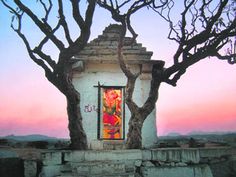 an old building with a painting on the window and tree branches in front of it