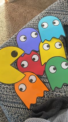 a group of colorful paper cut outs with eyes and mouths on them sitting on a couch