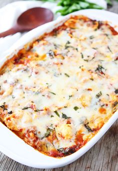 a casserole dish with cheese and spinach in it on a wooden table