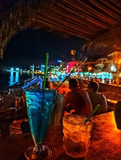 two drinks sitting on top of a table next to each other in front of a bar