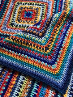 a multicolored crocheted blanket is laying on the floor