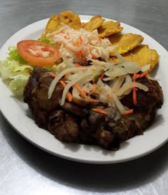 a white plate topped with meat and veggies next to potato chips on a table