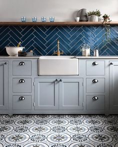 a kitchen with blue and white tiles on the walls, cabinets and countertops