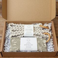 an open box with some items in it on a wooden table and the contents are wrapped in white yarn