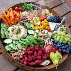 a wooden platter filled with assorted fruits and vegetables