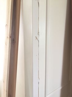 a white door with peeling paint on it in a room next to a wooden floor