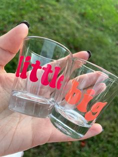 someone holding two glasses with the word little big on them