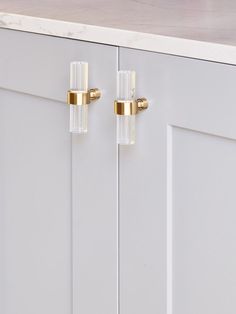 two glass door handles on a white cabinet