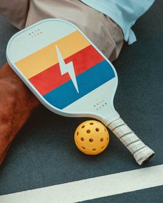 a person laying on the ground with a tennis racket and ball in front of them