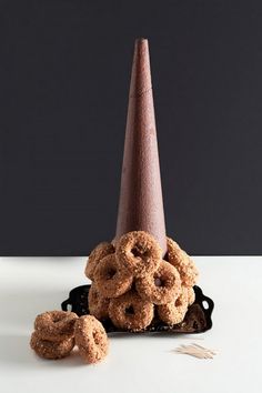 a pile of doughnuts sitting next to a cone on top of a table