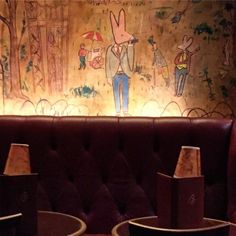 two lamps are sitting on the table in front of a wall with rabbits painted on it