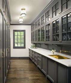 a large bathroom with wooden floors and gray cabinetry, along with white counter tops