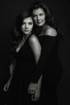 two women are posing for a black and white photo in front of a dark background