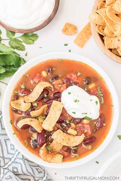 a white bowl filled with chicken tortilla soup and topped with sour cream on top