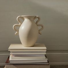 a white vase sitting on top of a stack of books