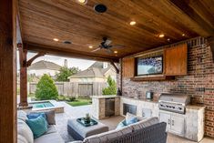 an outdoor kitchen and living room area with wood ceilinging, brick walls, and built - in grill