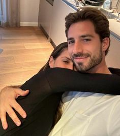 a man and woman hugging each other on the bed in front of a kitchen counter