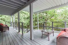 a covered porch with wicker furniture and trees in the background