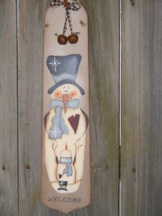 a painted snowboard hanging on the side of a wooden fence with an image of a penguin wearing a top hat