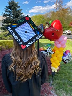 a woman wearing a graduation cap with balloons attached to her head and writing on it