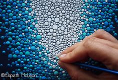 a hand is holding a pencil and drawing something on a piece of art that looks like bubbles