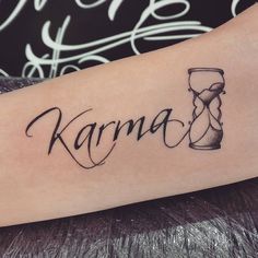 a tattoo with the word karma written in cursive writing and an hourglass