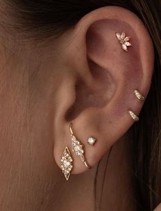 a woman with three different ear piercings on her left ear and one is gold